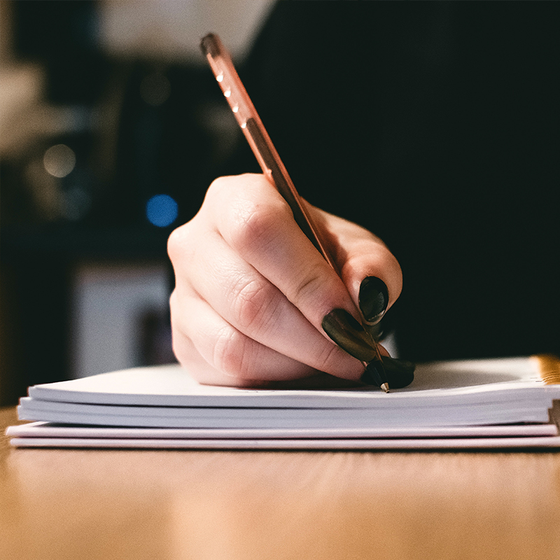 A hand writes on a page with a pen