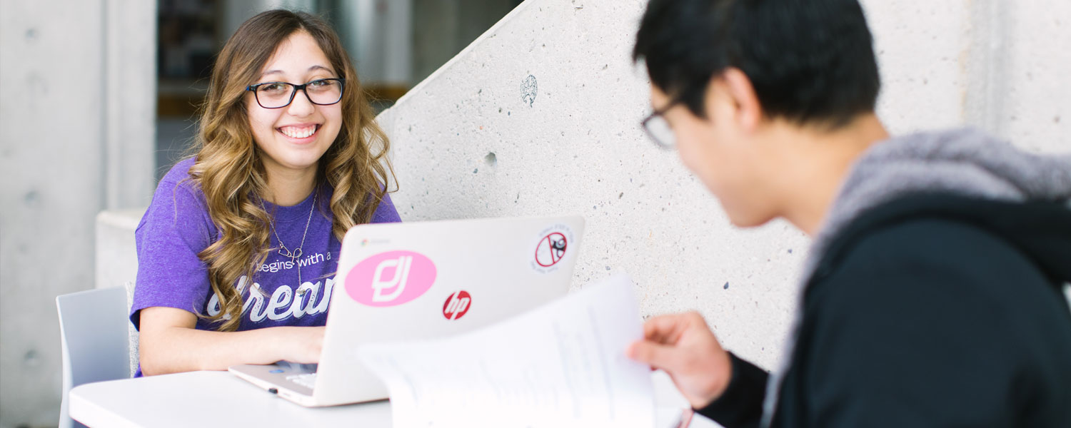 Image of two students studying and smiling