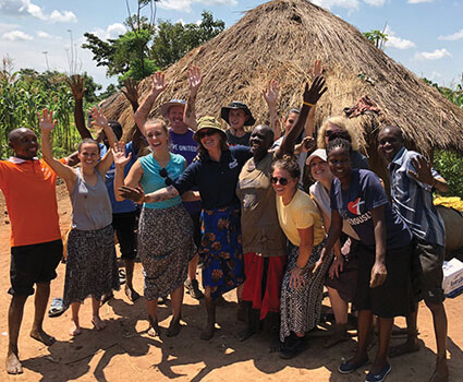 Weber State faculty, staff and students pose with community members in Ghana.