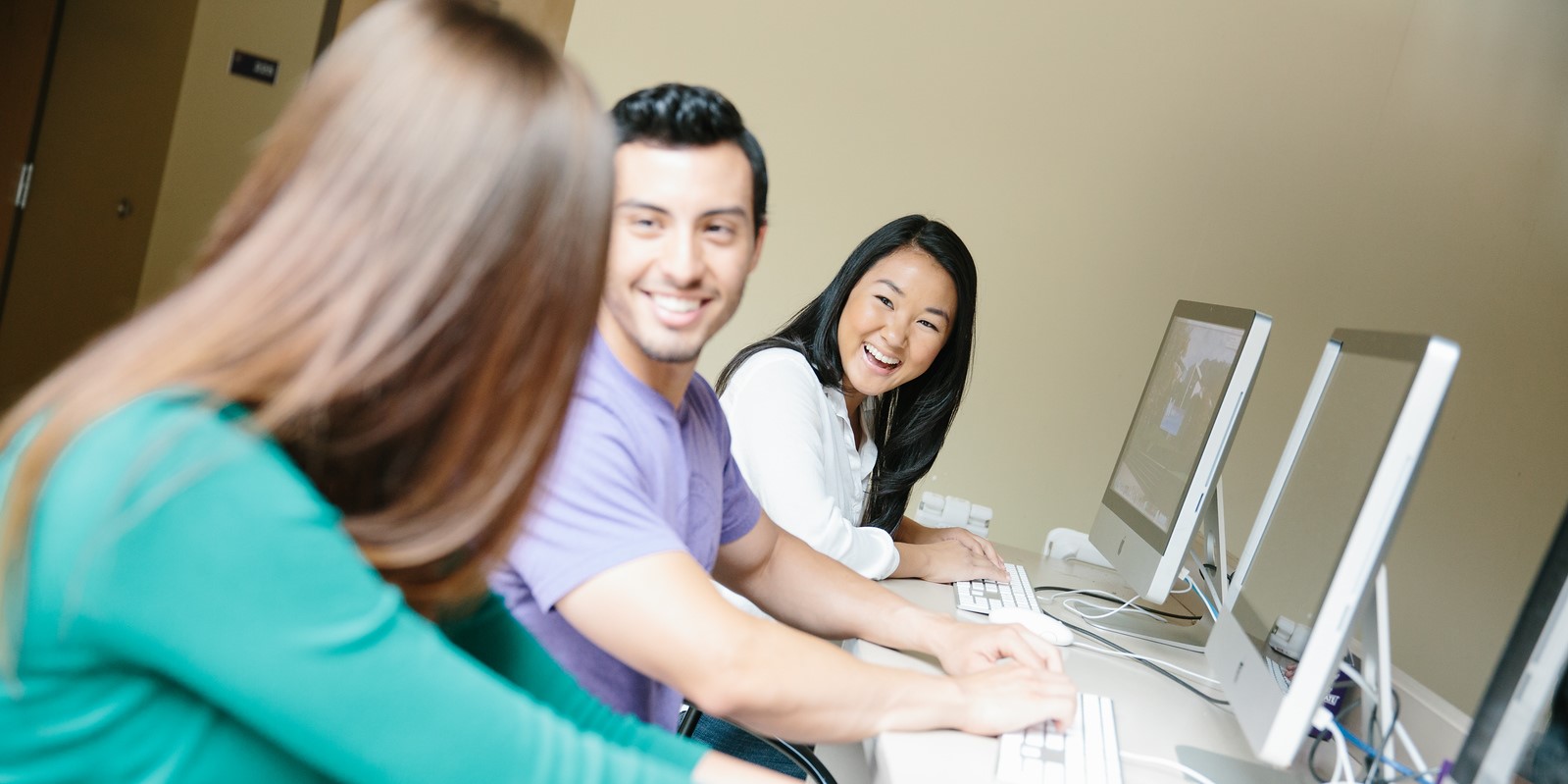 Two admissions counselors helping a student in a computer lab