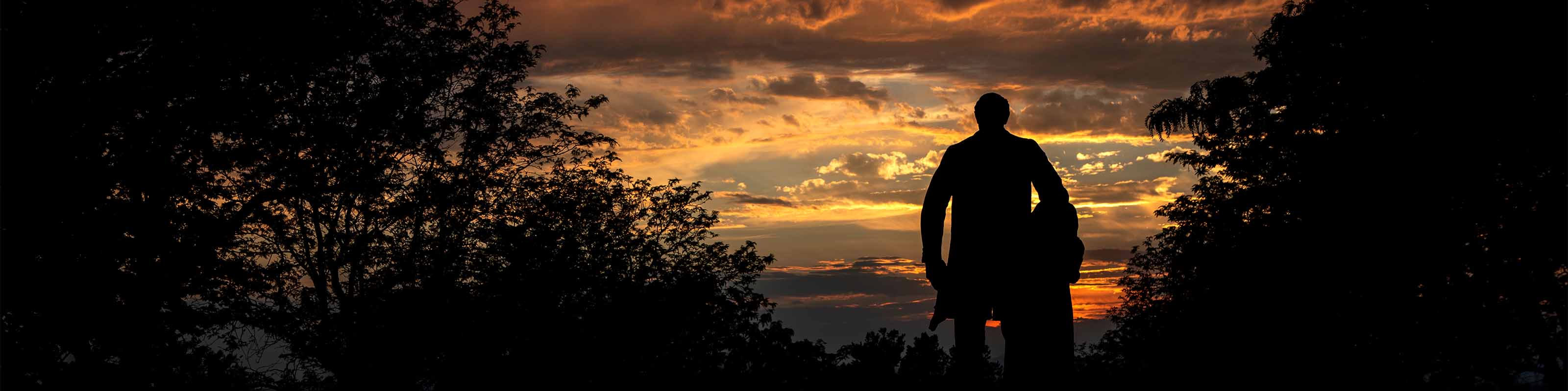 Moench Weber State University statue against sunset background.