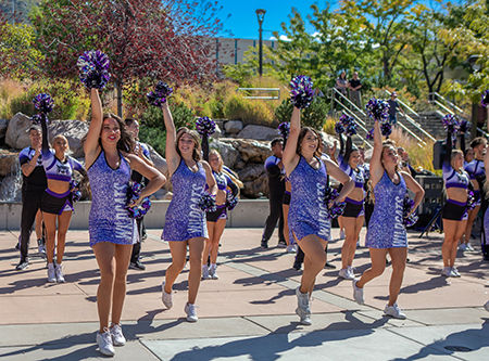 Weber State cheer team standing with pompoms.