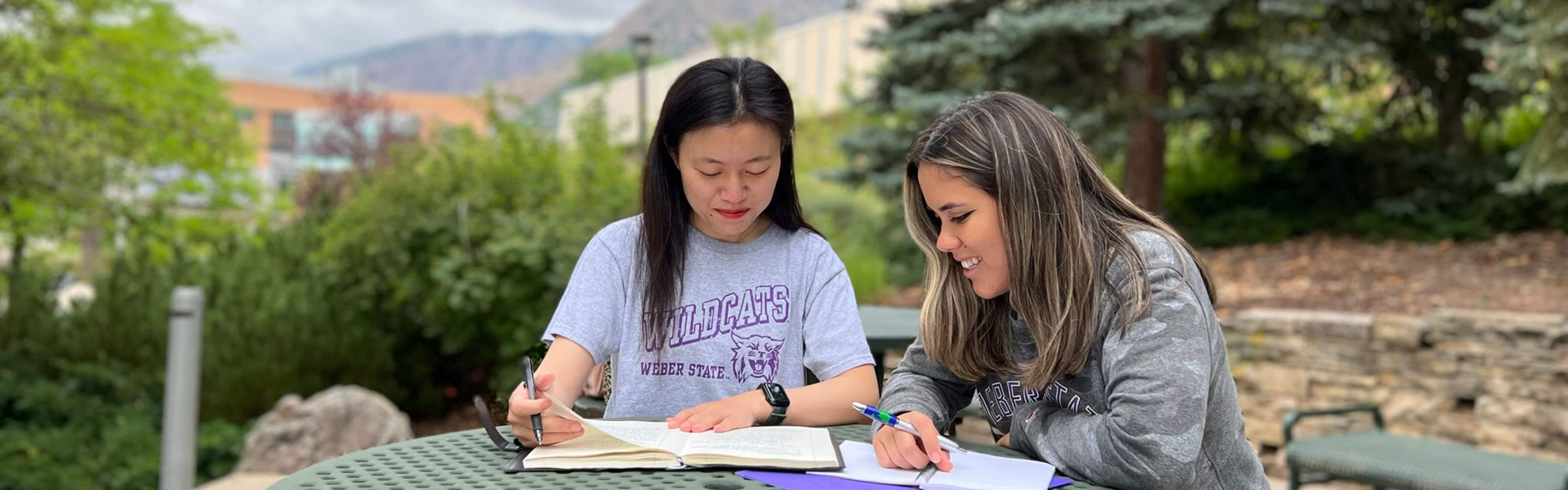 Two new students studying at a table outside at Weber State University.