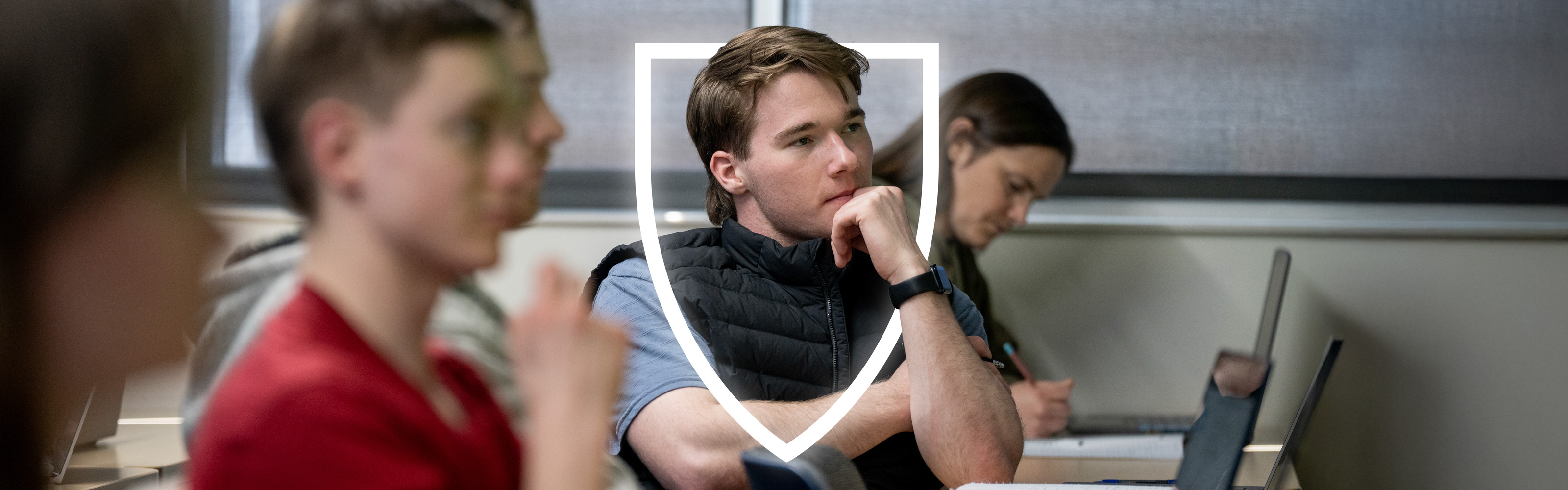 A student framed by a shield smiles in front of a waterfall on Weber State Ogden Campus.