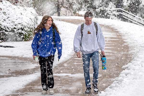 two students walk outside in the snow