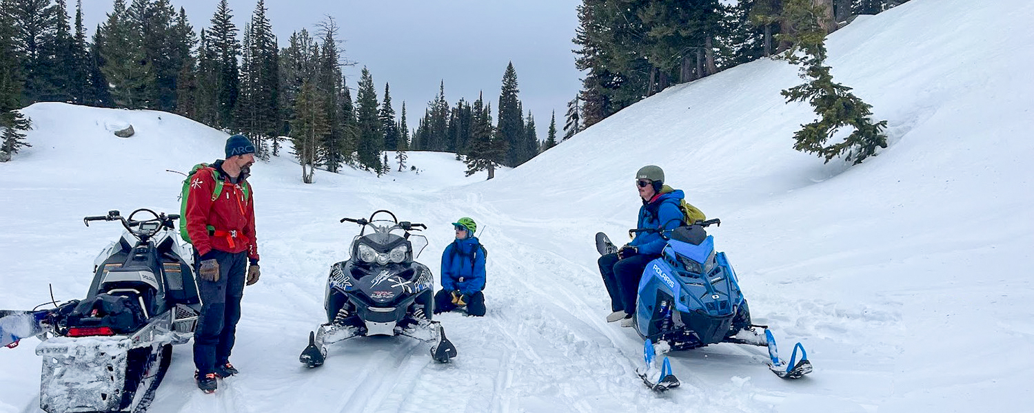 staff on a snowy path with snowmobiles