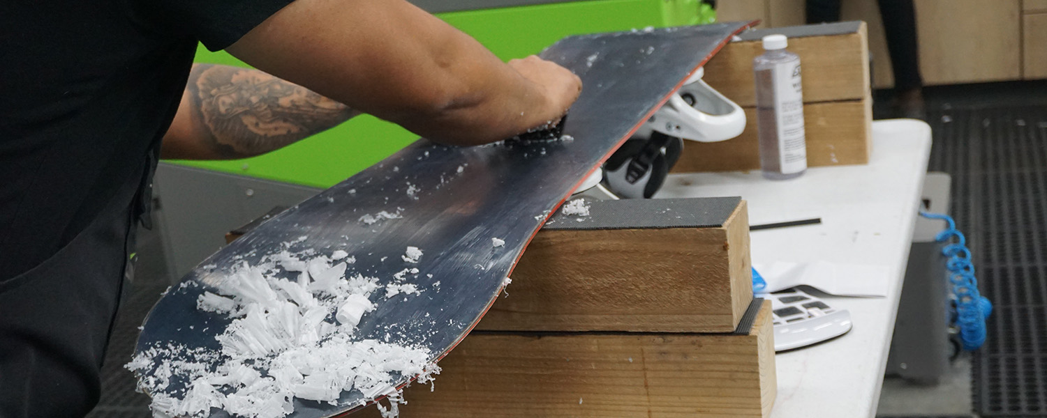 student tuning a snowboard