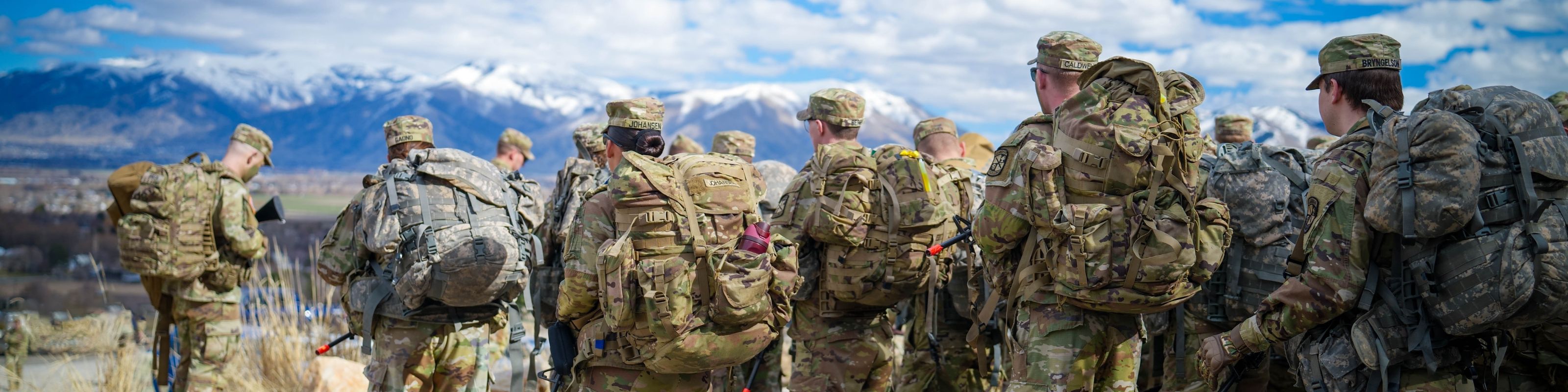 Cadets in uniform gathering outside with mountain views in the background