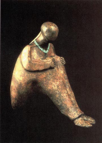 Color picture of bronze statue of a woman sitting on the ground.