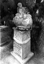 A photo of a tombstone with an angel sitting on top.